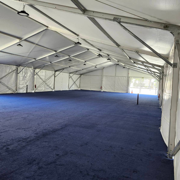 Spacious white outdoor tent with blue carpet flooring, ideal for events and gatherings.